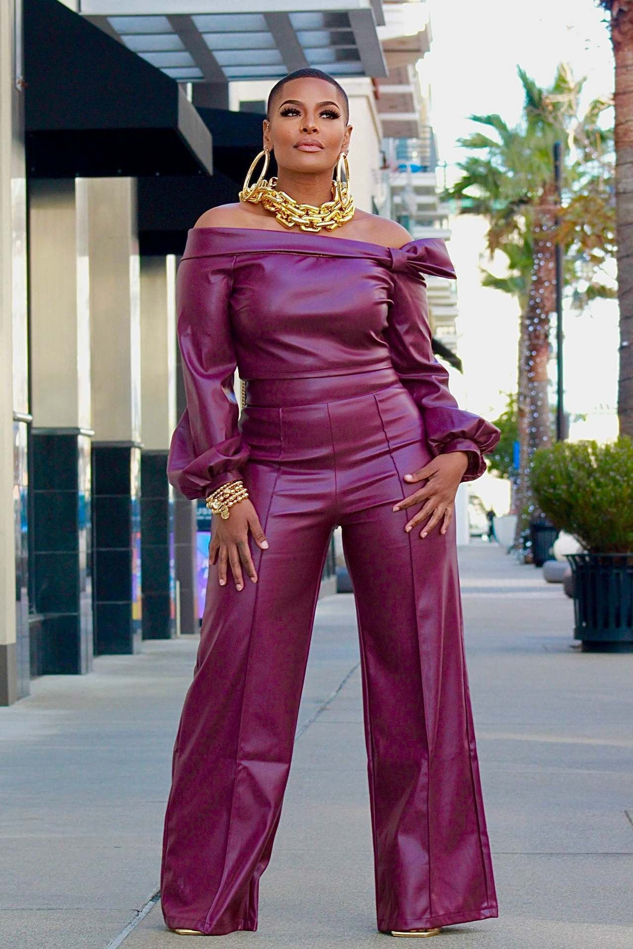 Front view of pants suit on a model: This faux leather pants suit offers a bold and trendy look for many occasions. The top features long sleeves that widen just before the cuffs for a unique touch. Its sleek design and comfortable fit provide the perfect balance of style and practicality.