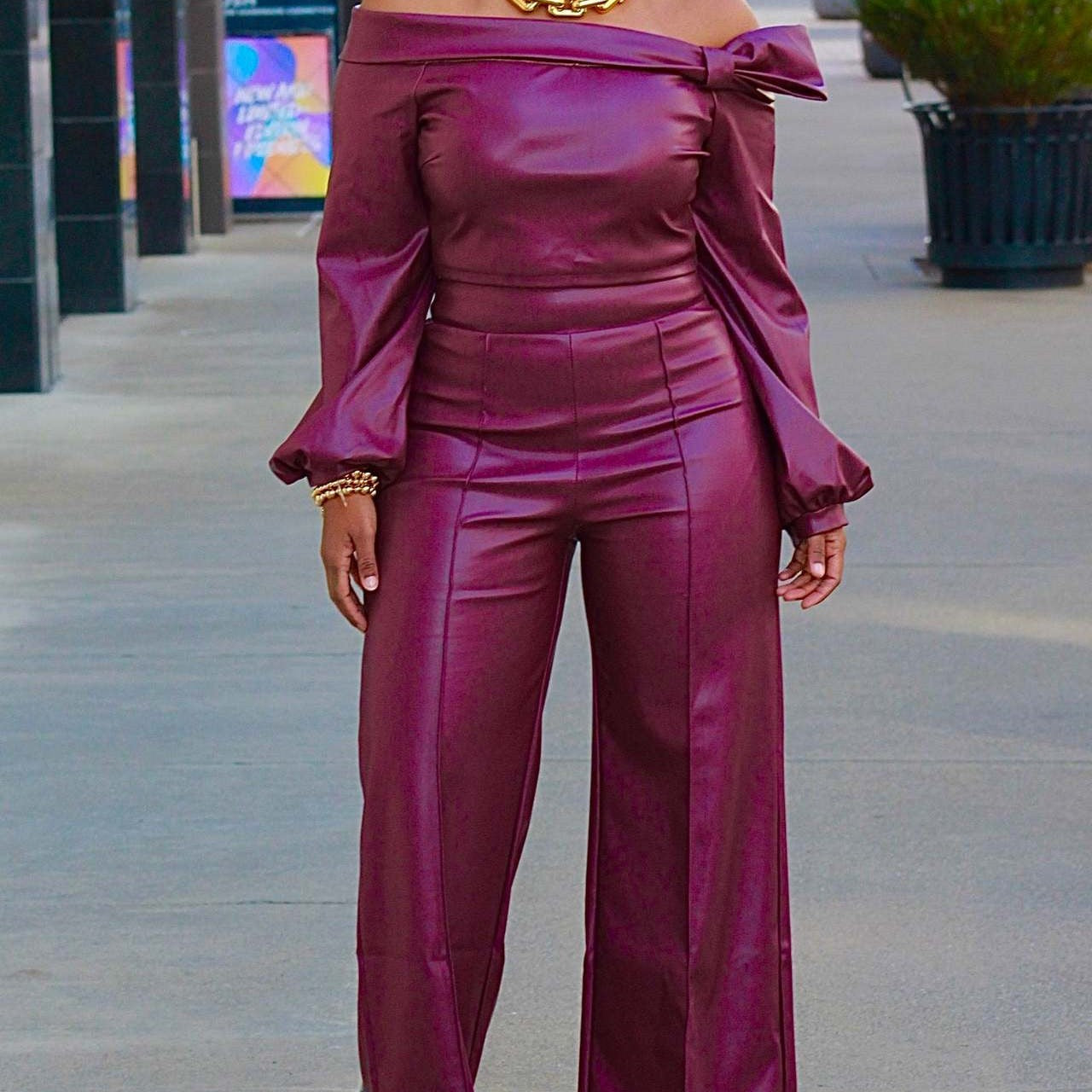 Front view of pants suit on a model: This faux leather pants suit offers a bold and trendy look for many occasions. The top features long sleeves that widen just before the cuffs for a unique touch. Its sleek design and comfortable fit provide the perfect balance of style and practicality.